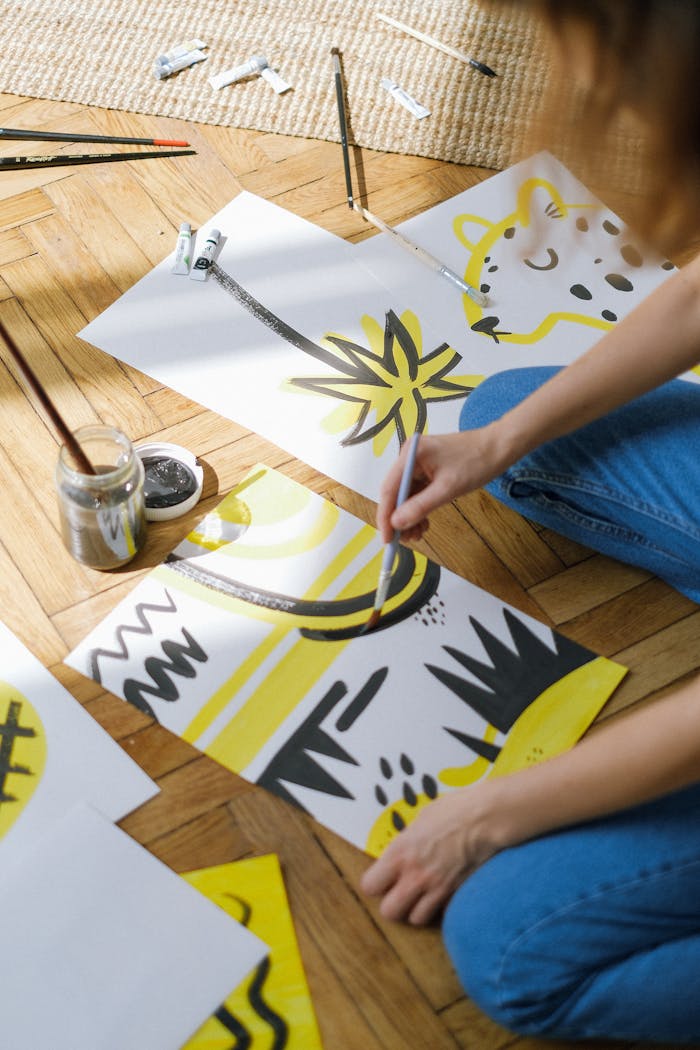 who-we-are A person painting abstract designs on paper in a bright, artistic studio.