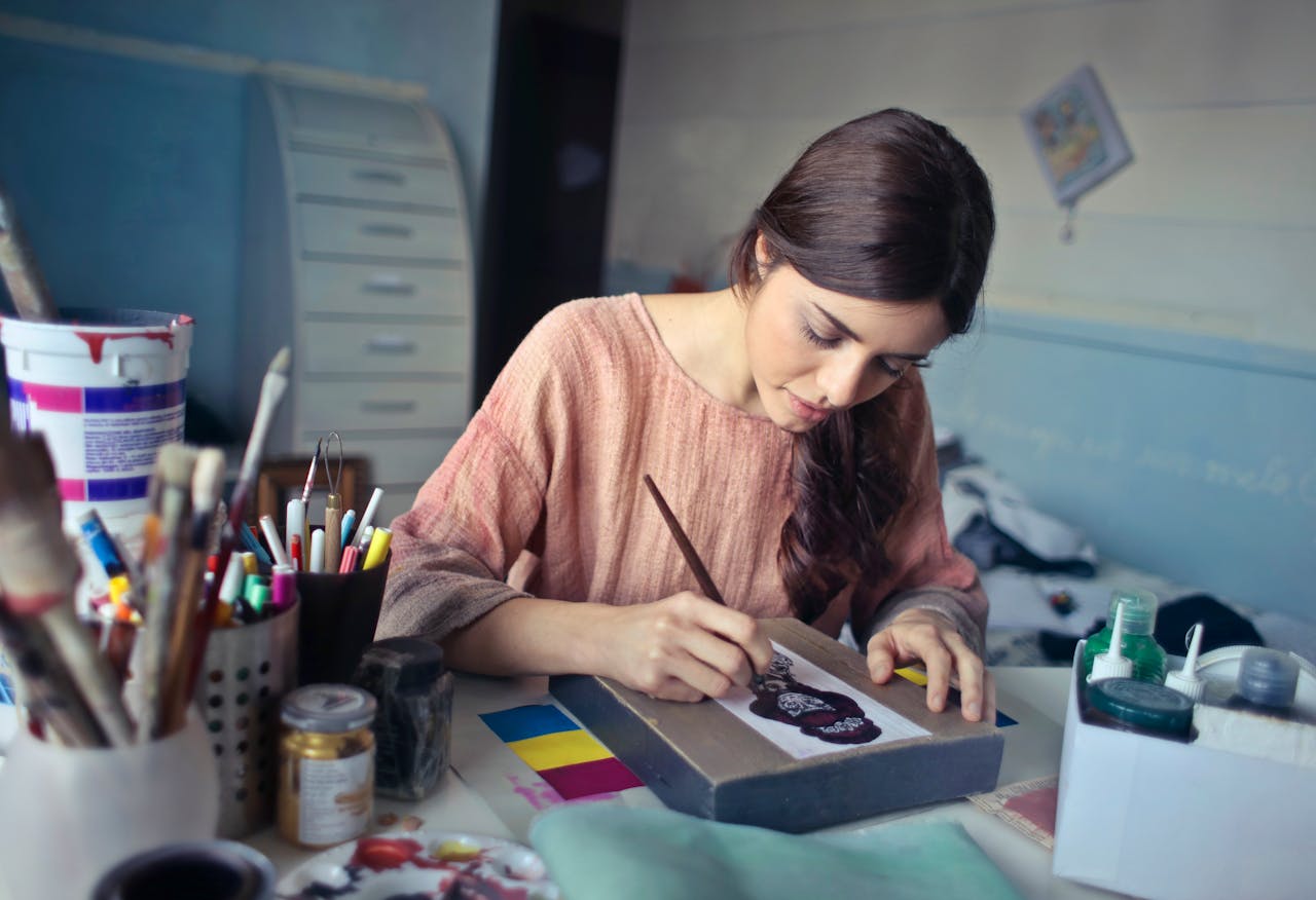 our-story Female artist deeply engaged in painting at her creative studio workspace.